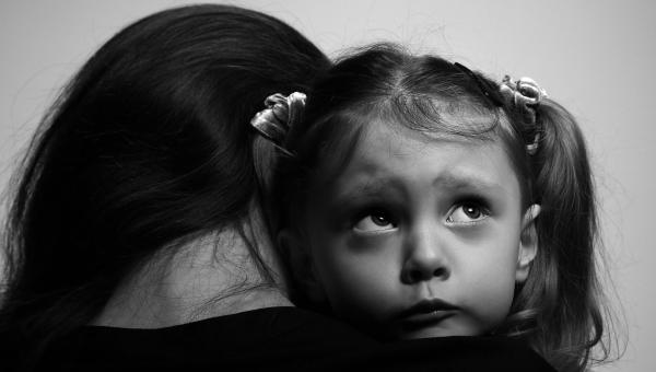Une femme victime de violences familiales porte sa fille dans ses bras