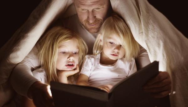 Papa lisant une histoire à ses deux fillettes