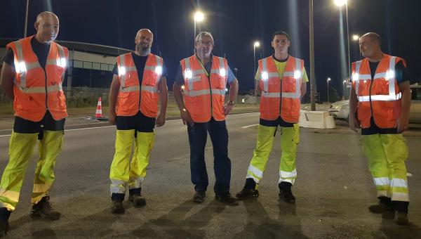 Les gilets haute visibilité sécurisent les agents de la direction des Infrastructures - l'équipe a revêtu les gilets à LED qui sont allumés. Ils fait nuit.