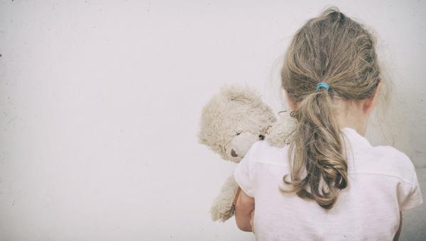 Enfant de dos serrant sa peluche contre elle