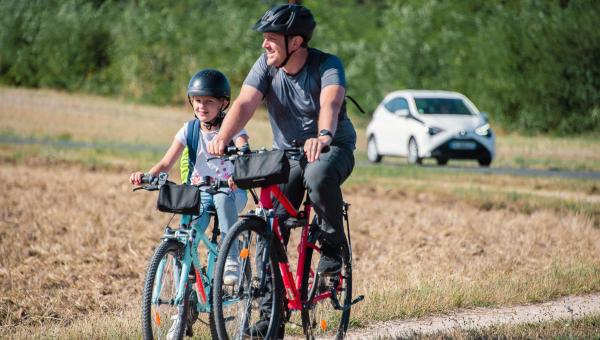 Cyclistes sur une route communale et voiture en arrière plan