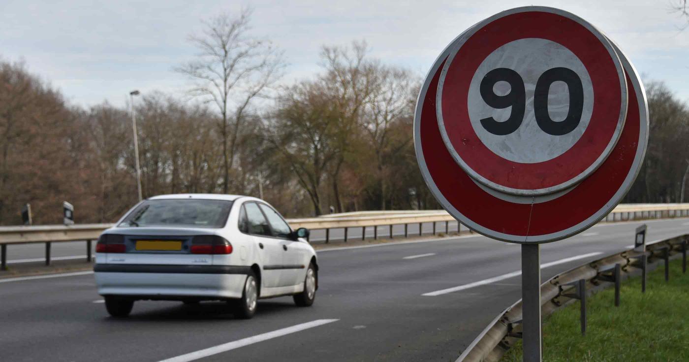 Route avec une voiture et un panneau de limitation de vitesse