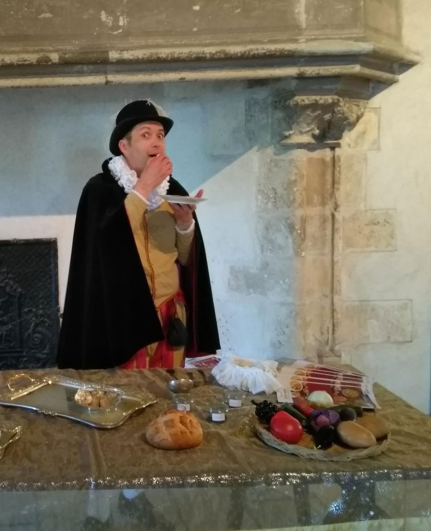 Dans une pièce su château de Sully, grande table garnie de nourriture, un homme du château en habit d'époque, s'apprête à manger.