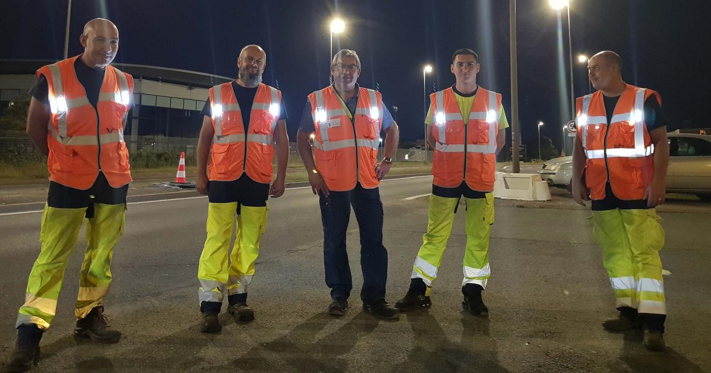 Les gilets haute visibilité sécurisent les agents de la direction des Infrastructures - l'équipe a revêtu les gilets à LED qui sont allumés. Ils fait nuit.