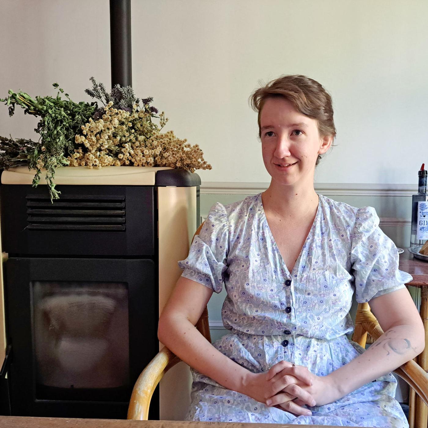 Aux bons vivres, à Yèvre-le-Châtel : un café associatif qui ne manque pas de piqué ! Anne-Claire assise à côté du poêle sur lequel il y a un bouquet de fleurs séchées