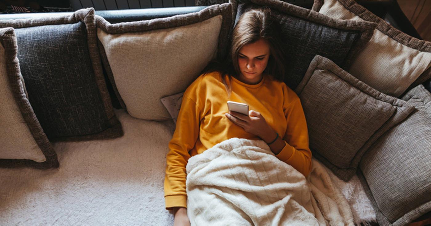 Moins d’écrans ? Un jeu d’enfant !? Jeune femme sur canapé