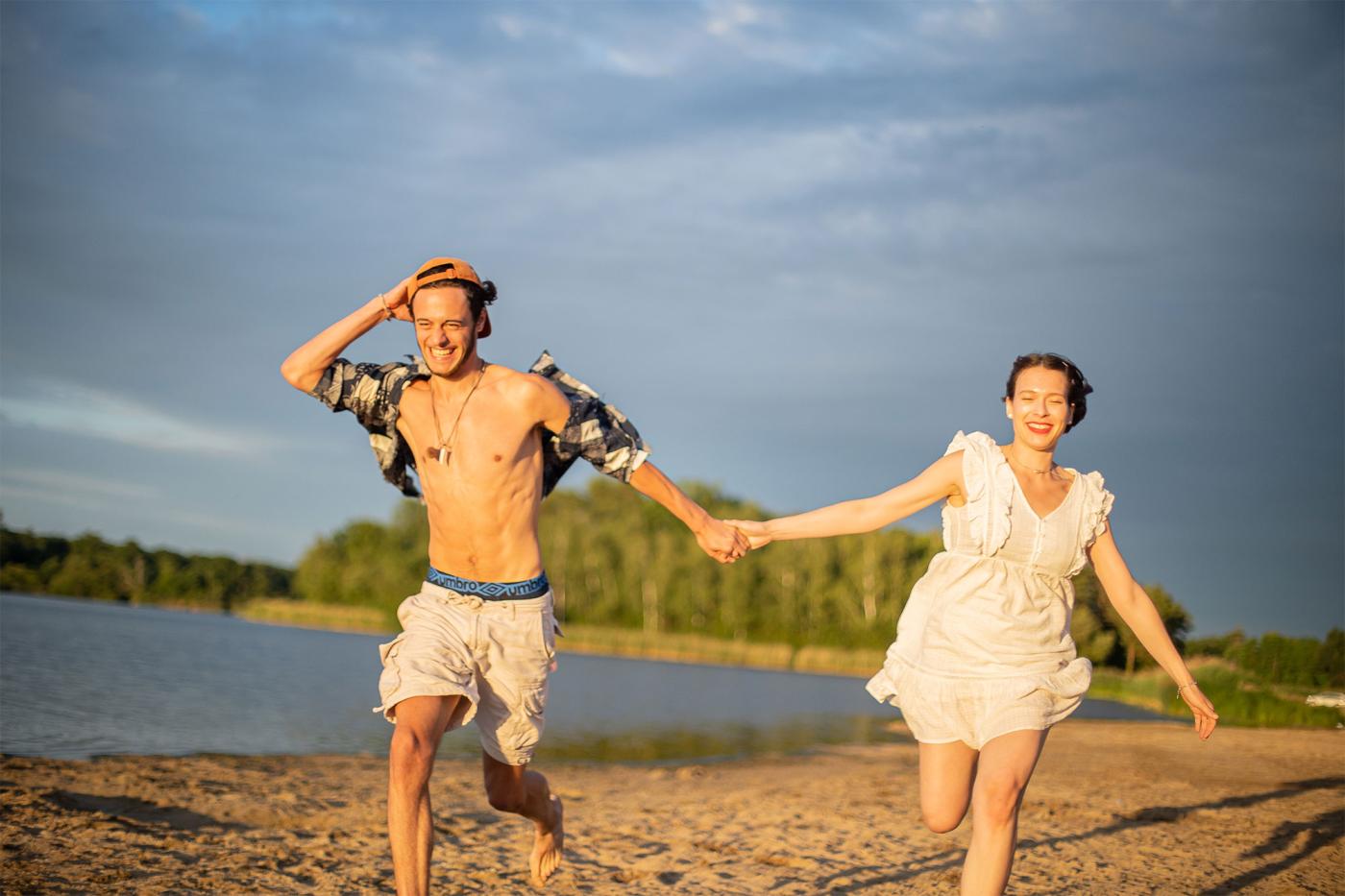 Photo de deux personnes qui cours sur la plage main dans la main en riant