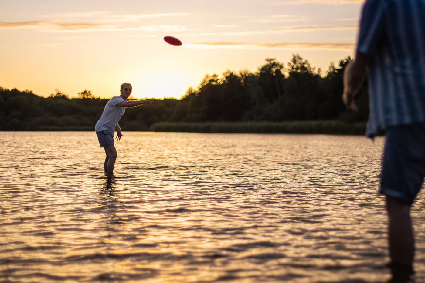 Photo de deux personnes qui jouent au frisbee dans l'eau