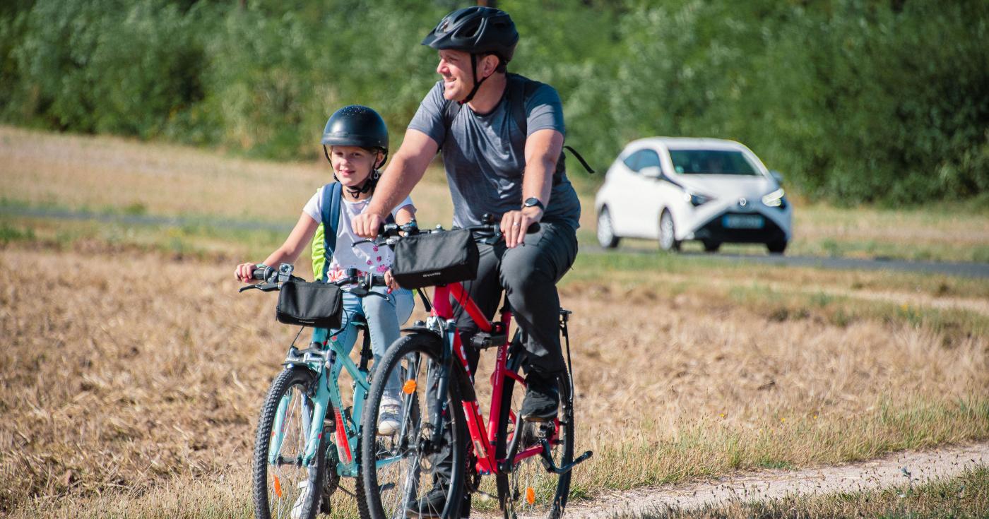 Cyclistes sur une route communale et voiture en arrière plan