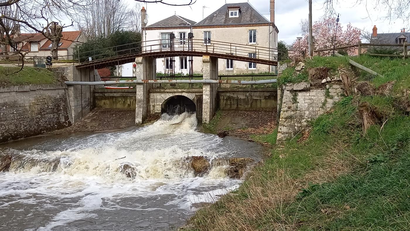 déversoir en pierre, avec deux vannes entrouvertes qui laissent passer le trop-plein d'eau du canal d'Orléans à Combleux.