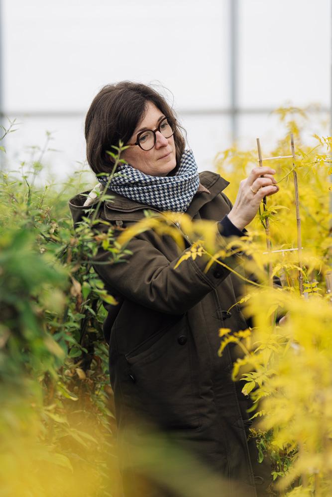 Marie-Laure dans sa ferme avec une plante grimpante qu'elle produit